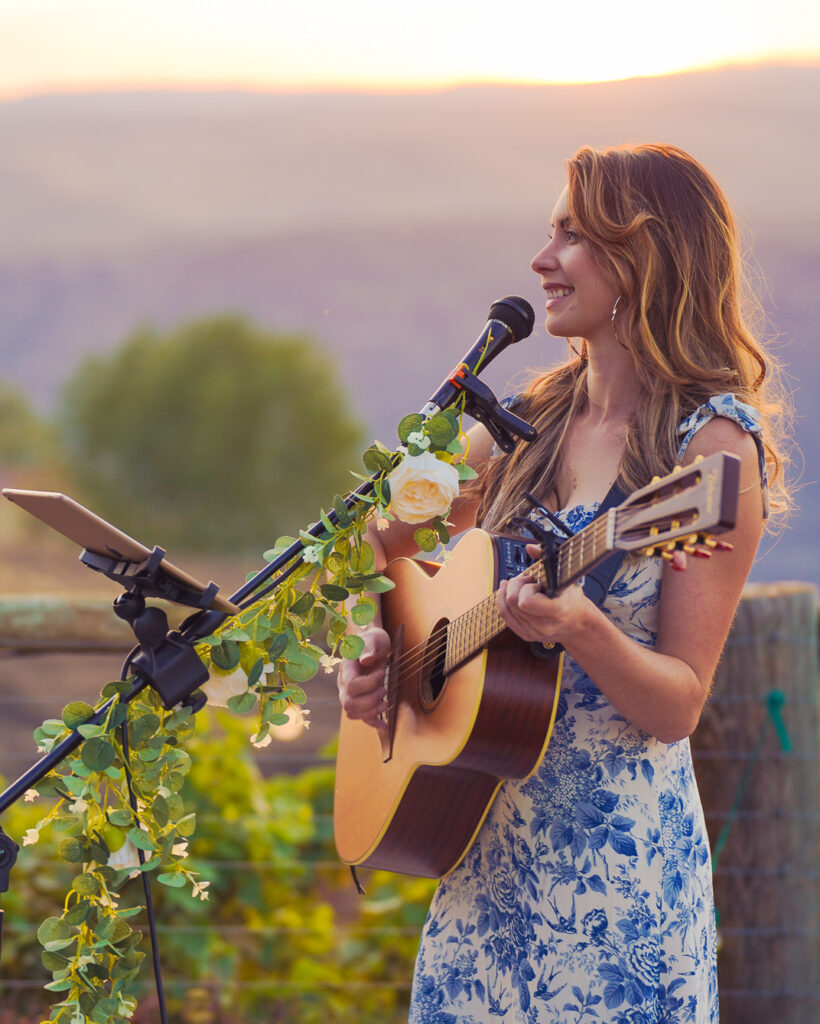 Woman playing guitar at sunset, in PNW mountains