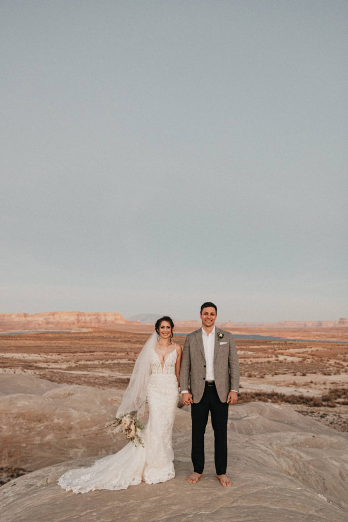 Husband and wife stand in desert canyon for adventure elopement in Lake Powell, AZ