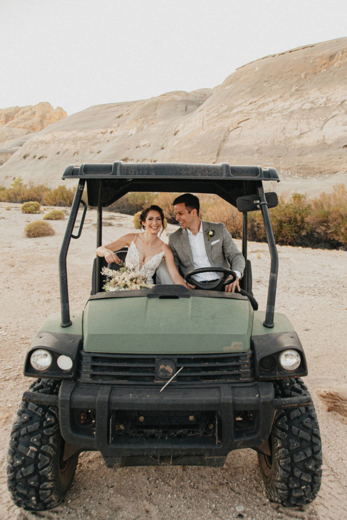 Husband and wife laughing and driving ATV in desert canyon on adventure elopement in Lake Powell, AZ