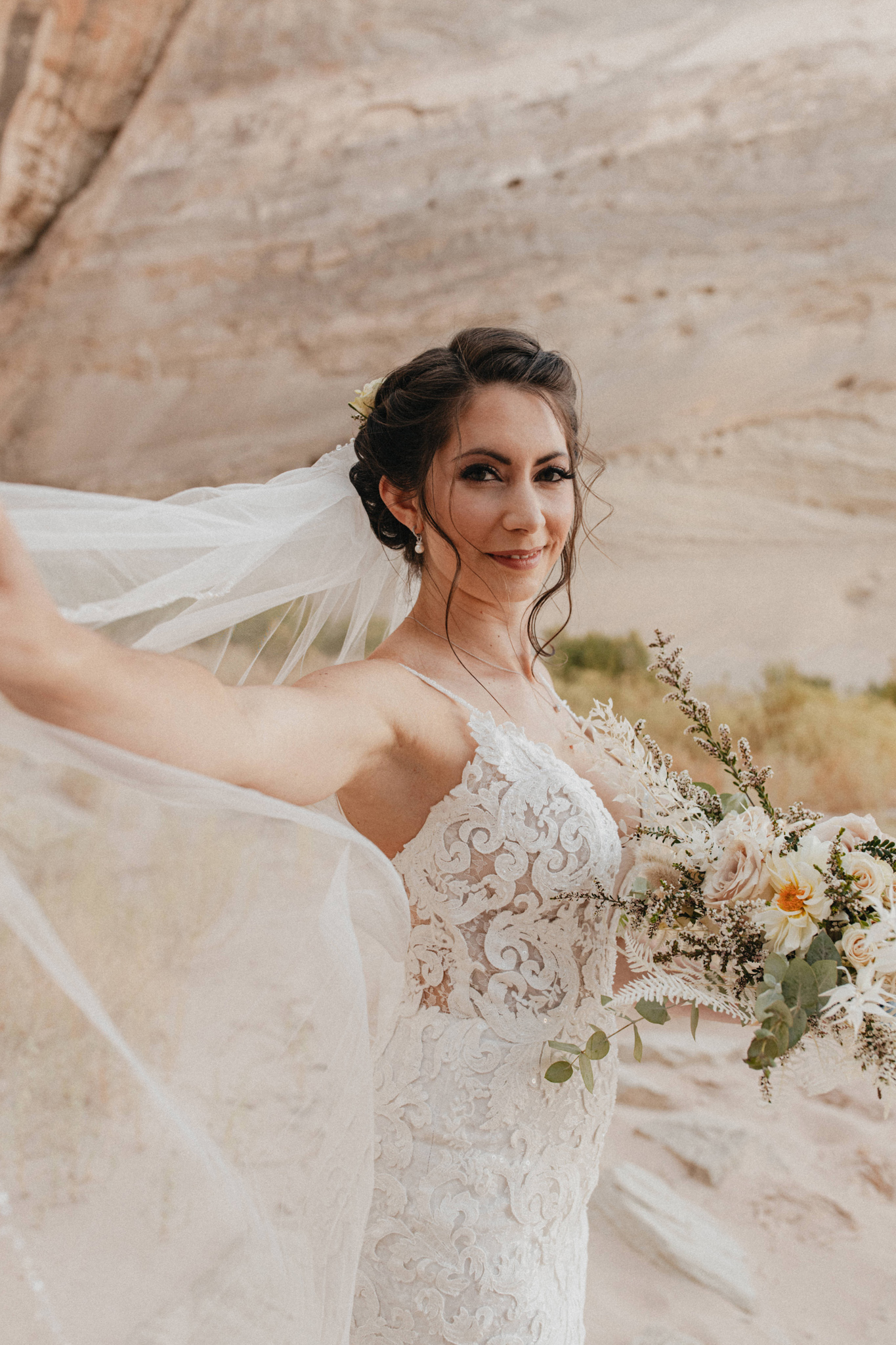 Bride holds veil in desert canyon on her adventure elopement in Lake Powell, AZ
