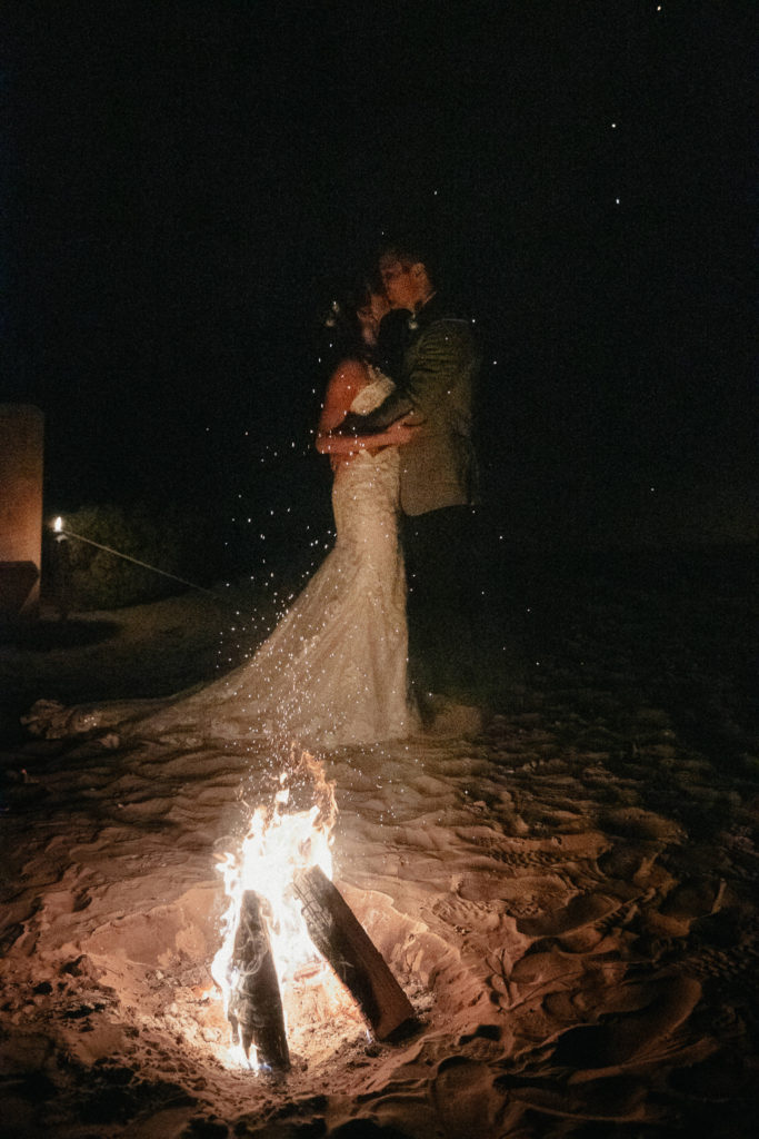Newlyweds dancing in front of camp fires during adventure elopement in Lake Powell, AZ