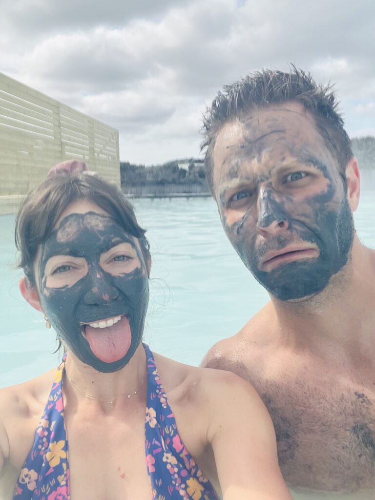 man and woman with mud mask in light blue water lagoon iceland