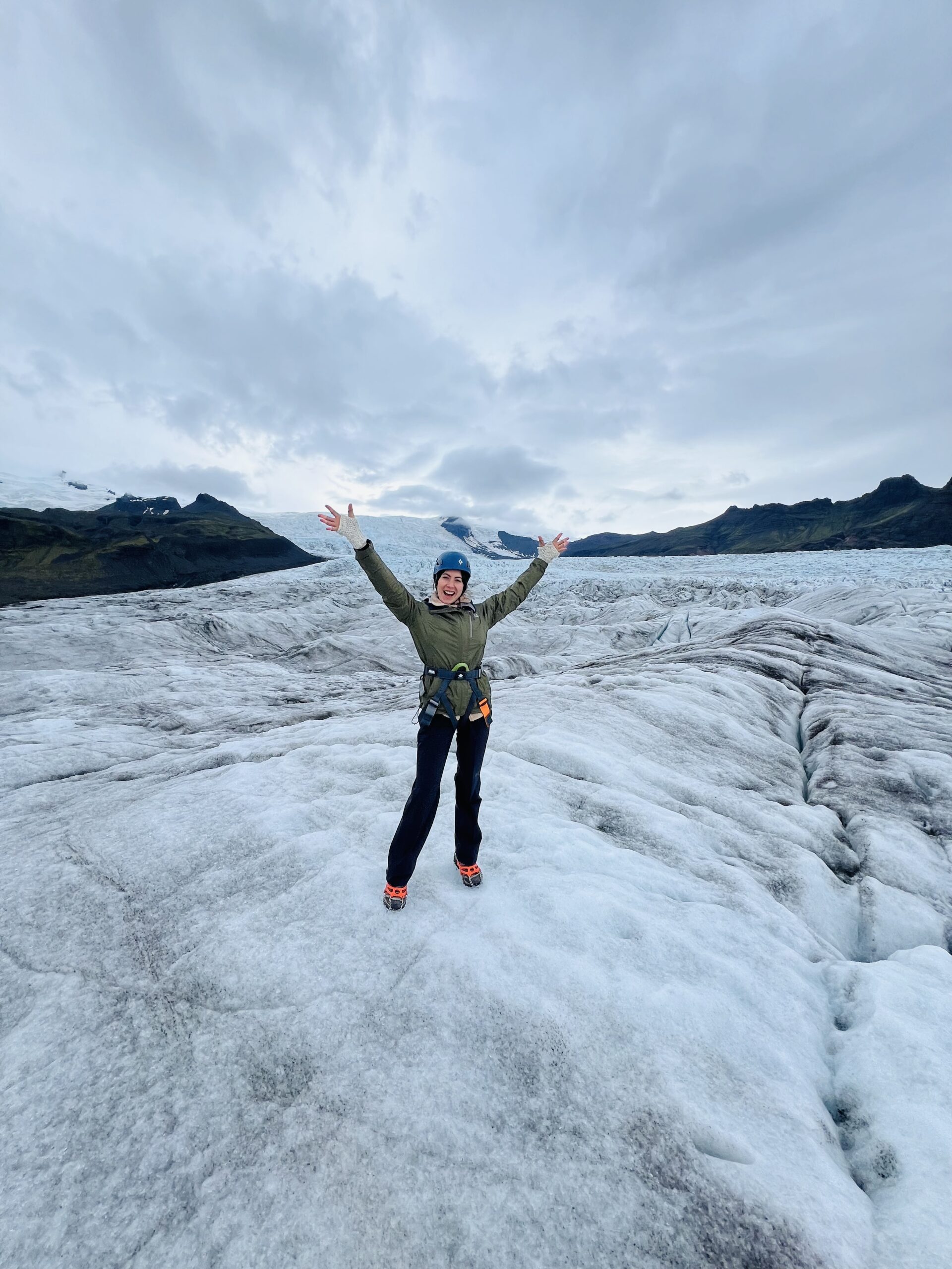 woman smiling with arms up on glacier