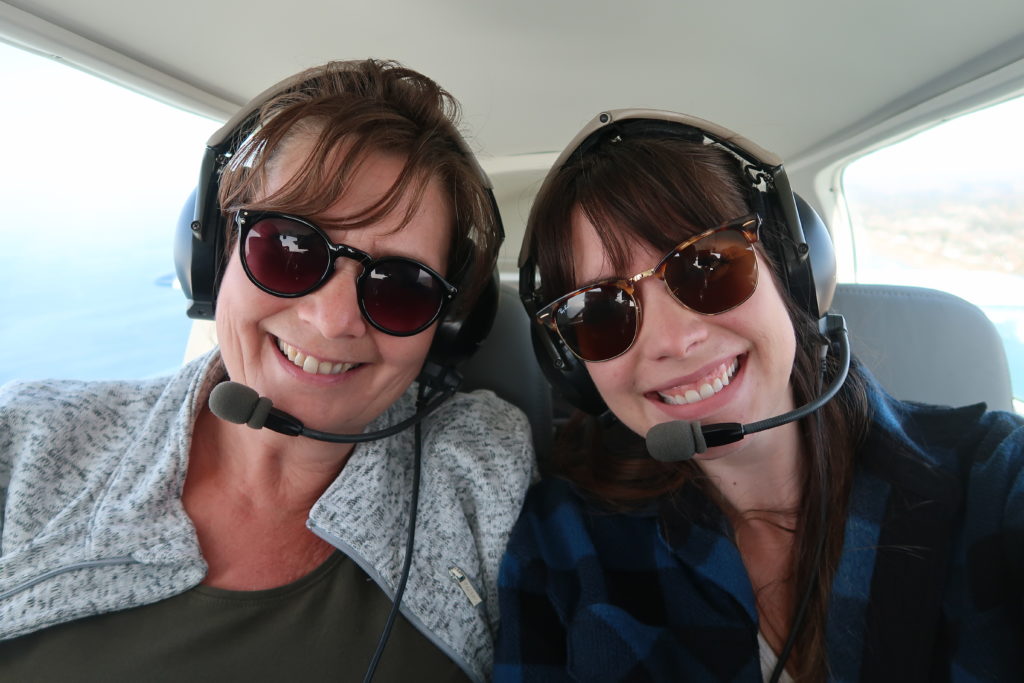 mother and daughter in tiny airplane flying over encinitas califoronia with sunglasses and headphones