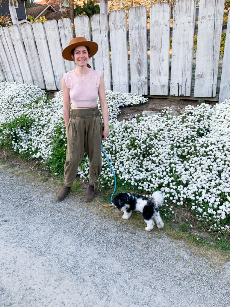 Woman walking her dog biewer terrier in front of white flowers in seattle washington